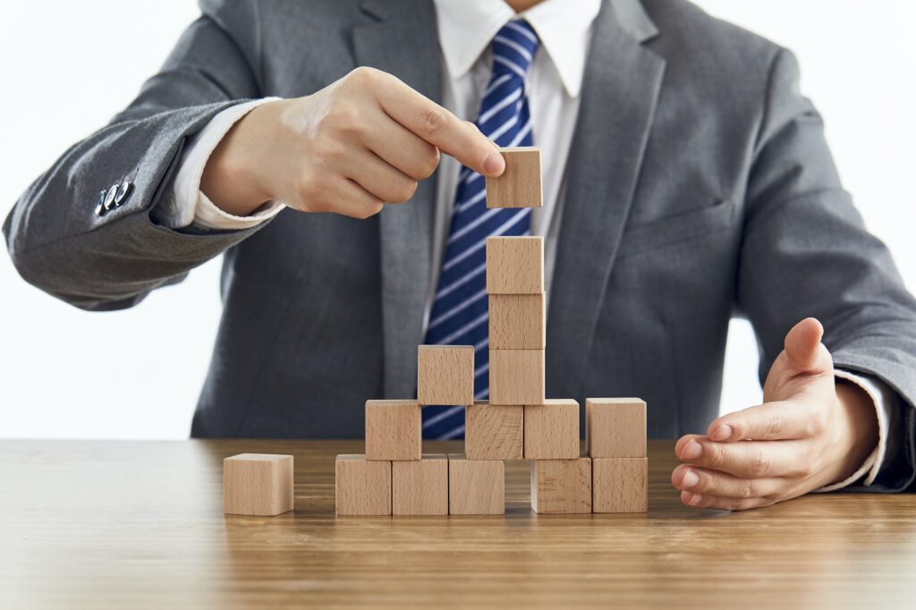 Businessman in a suit building a tower using wooden blocks - marketing strategy concept